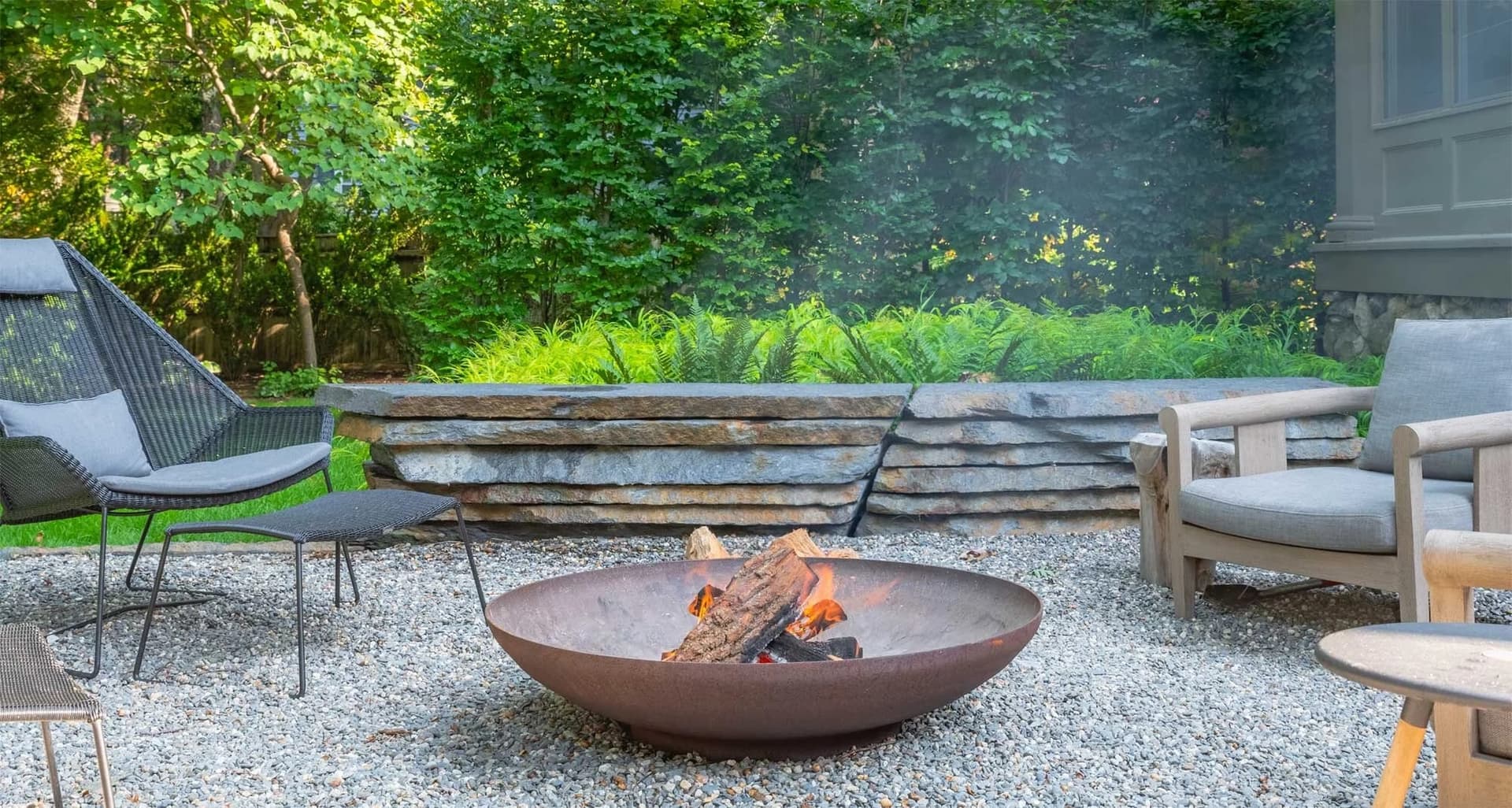 Stone patio with a fire bowl in Chestnut Hill, MA
