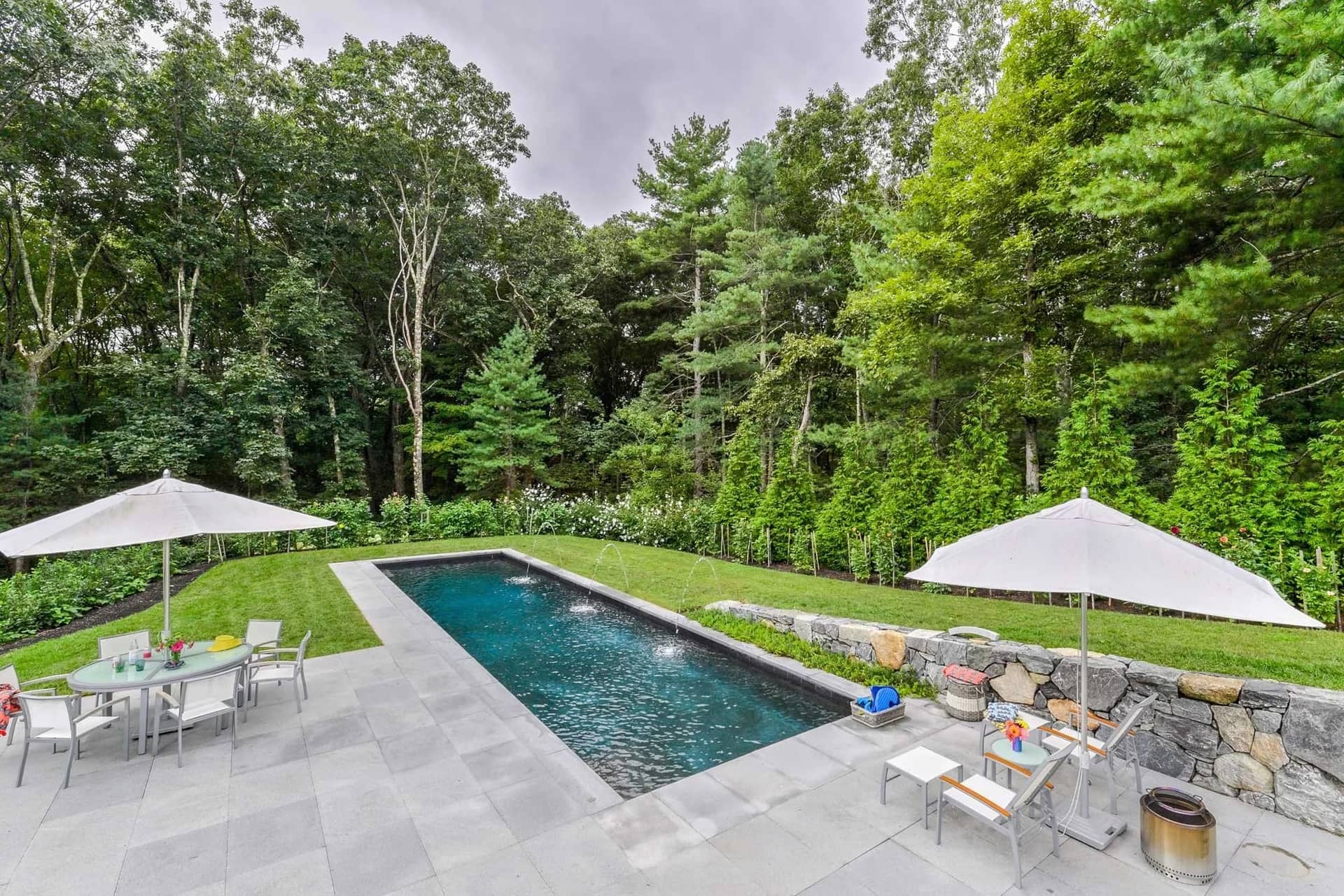 Bluestone pool terrace with a fieldstone retaining wall in Lincoln, MA