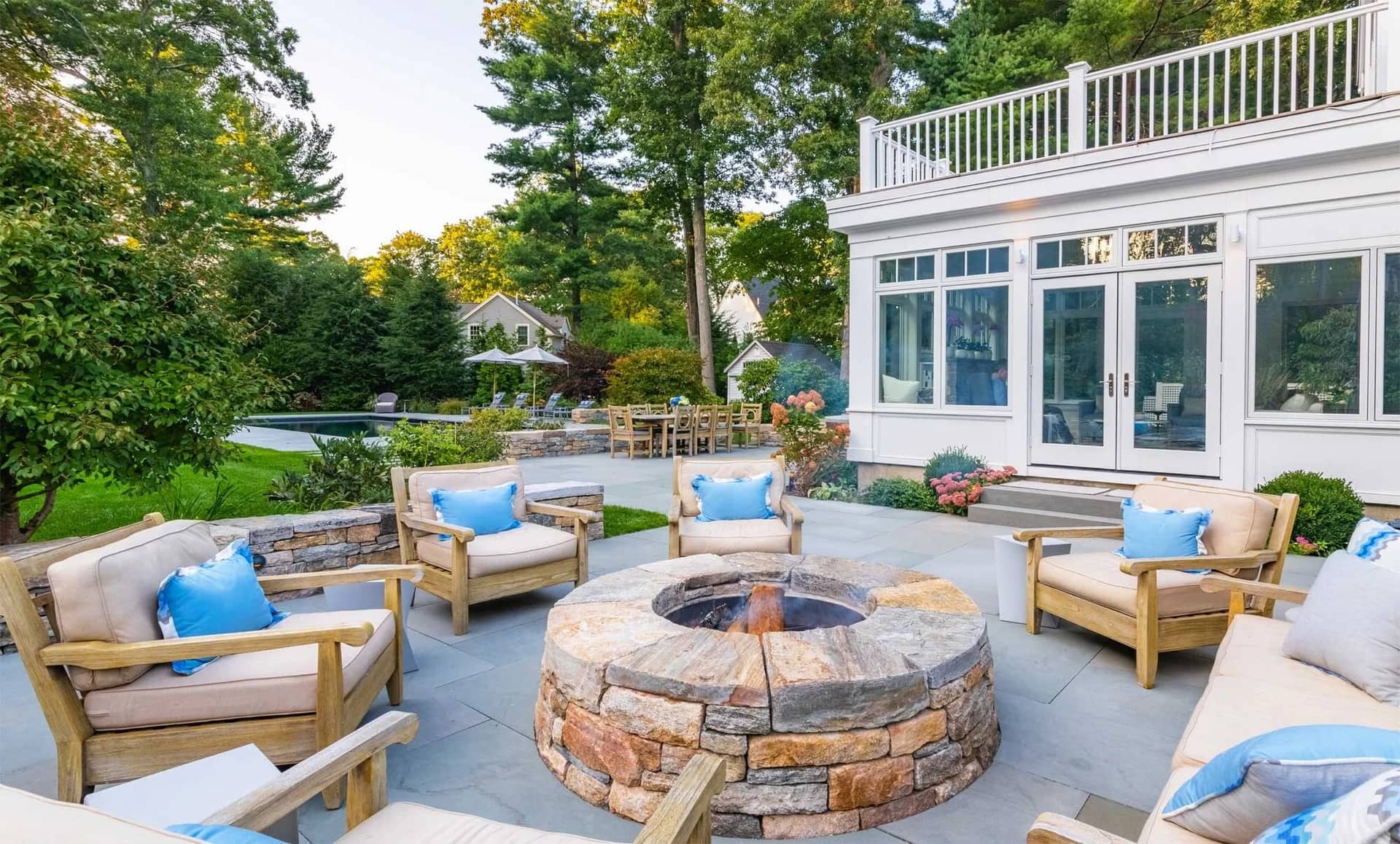 Round stone fire pit and seating on a bluestone terrace in Wellesley, MA